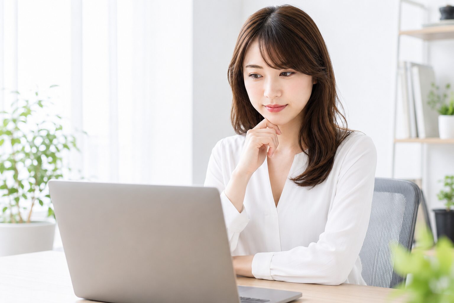 ノートPCで作業しながら困り顔で考える女性